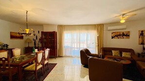 A spacious living room with a dining area, a sofa, and a ceiling fan. - SHR019 Gran Atico al lado de la playa (Torrox Costa)