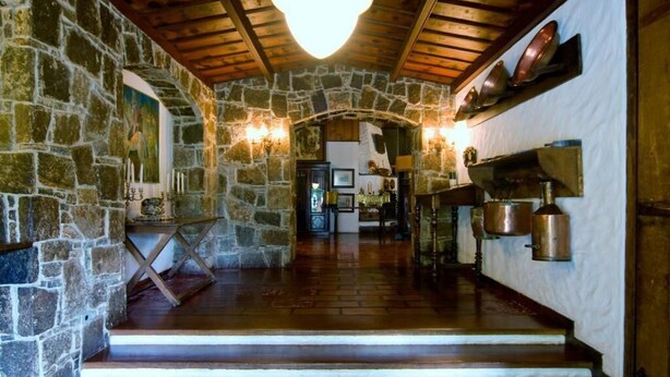 A stone-walled interior with wooden beams, a staircase leading to a kitchen area with pots and pans on the wall. - Hotel Terrazza (Campos do Jordão)