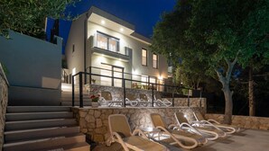 A modern building with a stone staircase leading to a balcony with lounge chairs and a table. - Gorgeous home in Kremena (Kremena)