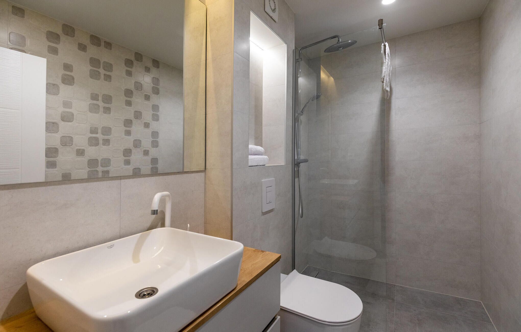 Une salle de bain moderne avec un lavabo blanc, des toilettes et une douche à parois de verre.