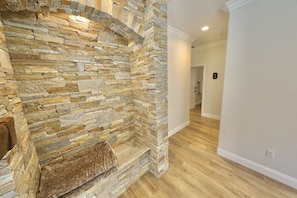 A stone fireplace with a bench, a wooden floor, and a white wall with a door labeled 'B'.