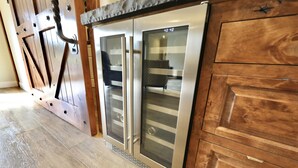 A modern kitchen with wooden cabinets and stainless steel appliances, including a refrigerator and oven. - Luxury Suite "A" (Redlands)