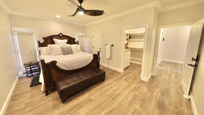 A bedroom with a wooden bed, a ceiling fan, and a walk-in closet. - Luxury Suite "A" (Redlands)
