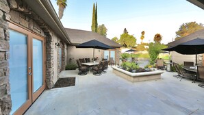 A patio area with stone walls, outdoor furniture, and umbrellas. - Luxury Suite "A" (Redlands)