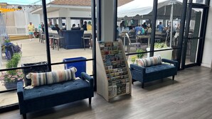 A modern indoor space with large windows, a reception area, and seating with a magazine rack. - The Ludlam (Sea Isle City)