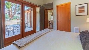 Ein Schlafzimmer mit Bett, Fenster und einer Tür, die auf eine Terrasse führt.