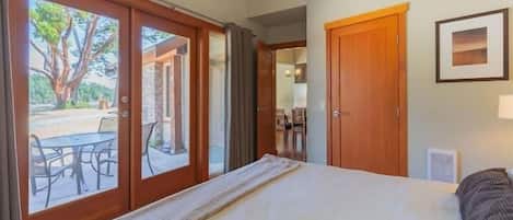 A bedroom with a bed, a window, and a door leading to a patio.
