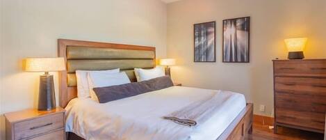 A neatly arranged bedroom with a wooden bed, bedside tables, and a dresser.