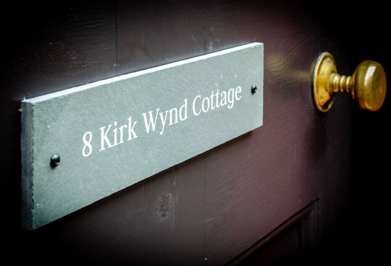 En dörr med en skylt som visar texten: ”8 Kirk Wynd Cottage”.