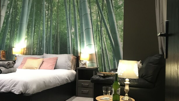 Um quarto com uma cama, mesas de cabeceira, uma luminária e uma estante.