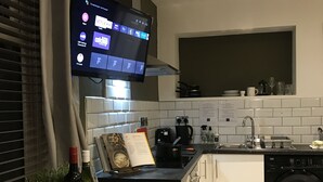 Uma cozinha moderna com televisão de tela plana montada acima do balcão, forno embutido, lava-louças e uma pia.