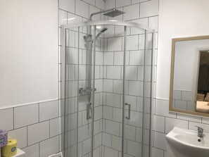 A glass-enclosed shower with a handheld showerhead and a wall-mounted faucet. - Contemporary 1 bed Studio for Comfy Stay in Wigan (Wigan)