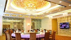 A banquet hall with round tables, chandeliers, and a television screen. - Hotel Fisher (Guangzhou)