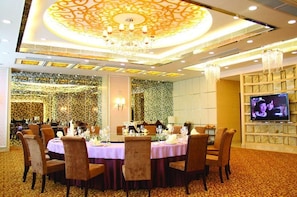 A banquet hall with round tables, chandeliers, and a television screen. - Hotel Fisher (Guangzhou)