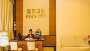 A reception desk with a sign reading 'BUSINESS CENTER' in a hotel lobby. - Hotel Fisher (Guangzhou)