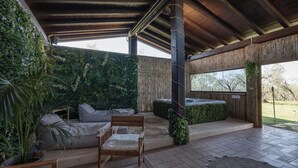 Un espace extérieur aménagé, abrité et doté d’un banc en bois, d’un canapé confortable et d’un jacuzzi.