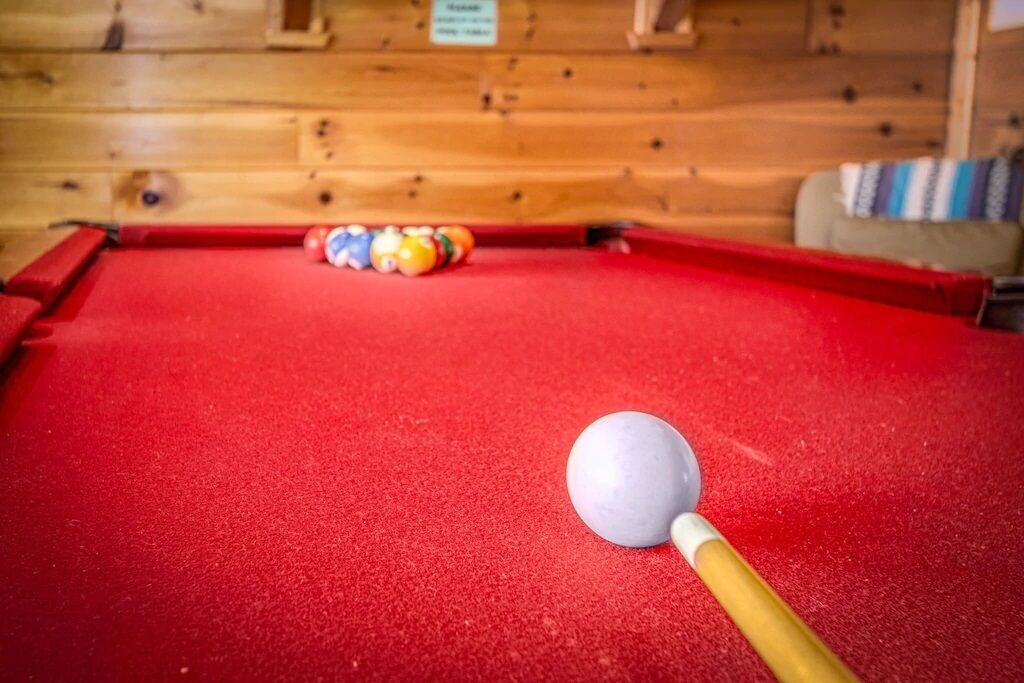 A pool table with a red felt surface, a cue ball, and colorful balls in the background.