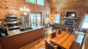 Ein Holzblockhaus-Innenraum mit Küche, Essbereich und Kamin.