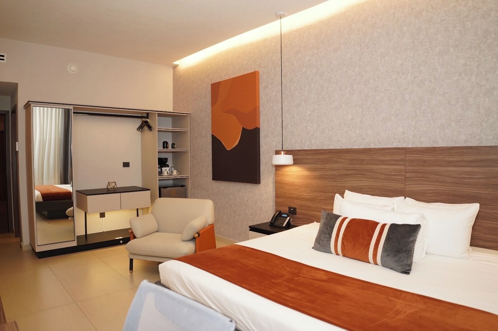 Une chambre d’hôtel avec un lit, une chaise, un bureau, une armoire et un tableau au mur.
