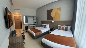 Une chambre d’hôtel avec deux lits, un bureau, une télévision et un miroir.