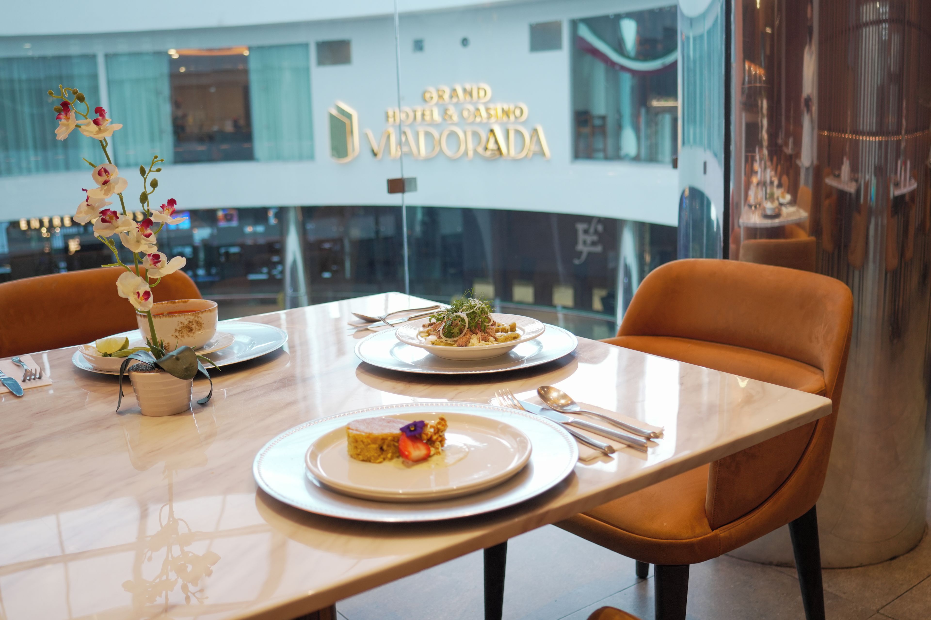 Una mesa de comedor con platos, cubiertos y una decoración floral en un hotel.