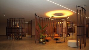 Un hall d’entrée moderne doté d’un luminaire circulaire, de cloisons en bois et d’espaces aménagés pour s’asseoir.