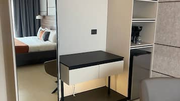 Una habitación moderna con escritorio integrado, perchero, cama con vistas y cafetera.