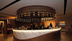 Un comptoir d’accueil moderne, doté d’un plateau en marbre, entouré d’un décor en panneaux de bois et éclairé par un système d’éclairage d’ambiance.