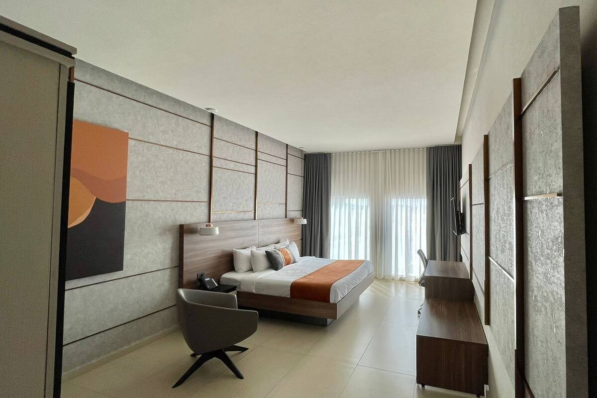 Una habitación de hotel moderna con una cama, un escritorio, una silla y un televisor.