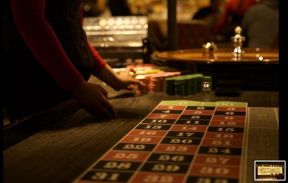 Une roulette avec des cases numérotées et une main qui place des jetons sur le tapis.