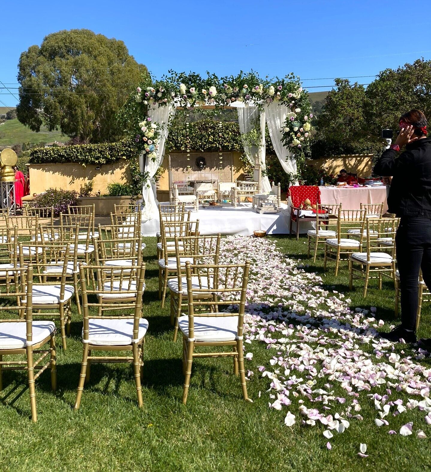An outdoor wedding ceremony with a floral arch and chairs arranged in rows.