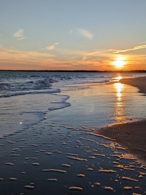 En strand vid solnedgången, där vågorna försiktigt sköljer in mot stranden.