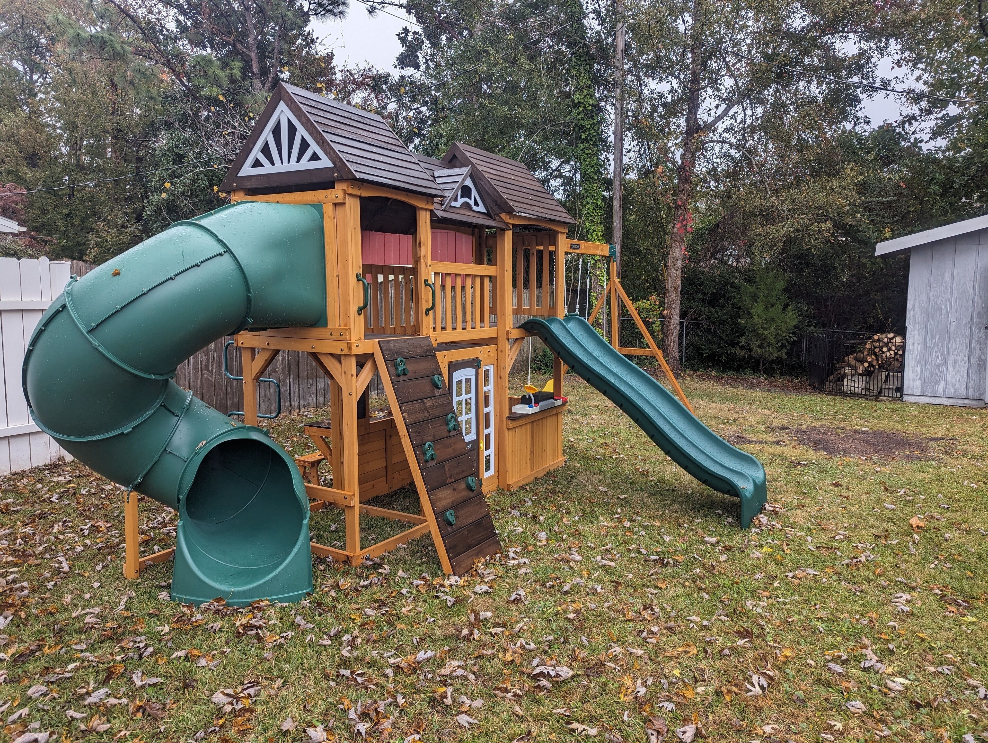 A wooden play structure with a green slide and a small platform.