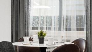 Un comedor con una mesa redonda, cuatro tazas blancas, una pequeña planta en maceta y dos sillas.