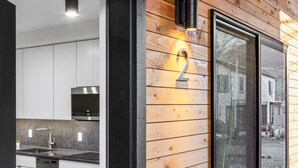 Una cocina moderna con armarios blancos, horno de acero inoxidable y campana extractora negra.