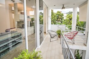 A modern interior with a glass door leading to a balcony, a staircase, and a seating area with chairs.