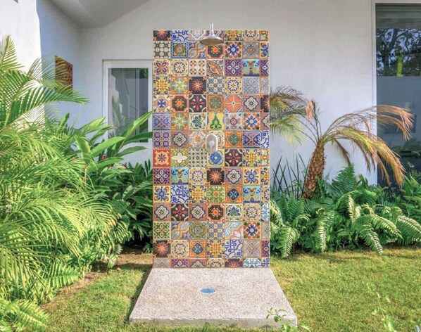 A vertical mosaic wall with a variety of patterns, surrounded by greenery and a house. - Golden Zone 1BR King Suite w/ Pool + Walk to Beach (Bucerías)