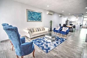 A modern living room with a beige sofa, blue armchairs, and a coffee table.