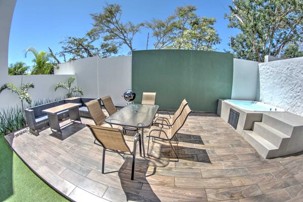 An outdoor patio with a round table and chairs, a barbecue grill, and a built-in seating area.