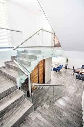 A modern interior with a glass staircase leading to a second-floor area.