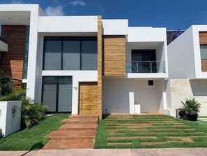 Un immeuble résidentiel moderne à plusieurs étages, doté d’un toit plat, de grandes fenêtres et d’une pelouse bien entretenue.