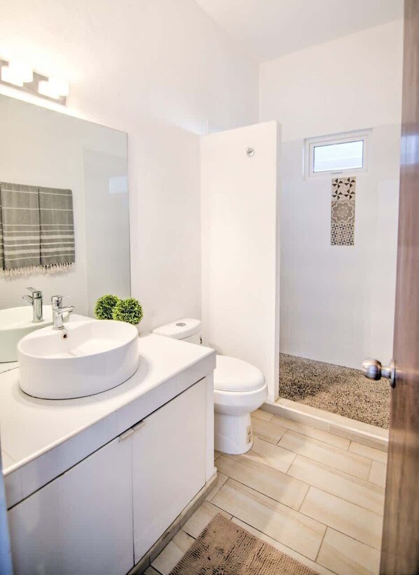 A modern bathroom with a large mirror, a round sink, a toilet, and a shower area. - Maravilla 1A: Golden Zone 1BR - 2 Blocks to Beach (Bucerías)