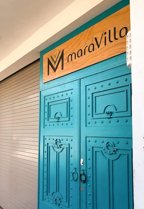 A teal door with a wooden sign above it that reads 'maraVilla'.