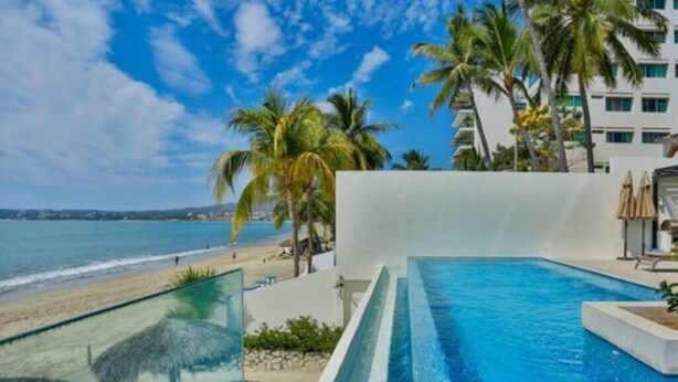 Una piscina con vista despejada a la playa y al océano.