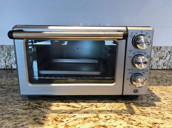 A Oster toaster oven on a granite countertop.