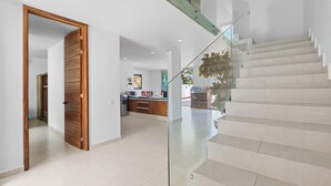 Un interior moderno con una escalera, una zona de cocina y una puerta de madera.