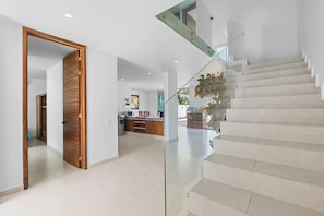 A modern interior with a staircase, a kitchen area, and a wooden door.