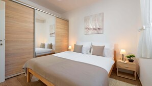 Quarto moderno com uma cama grande, um guarda-roupa de portas deslizantes, uma mesa de cabeceira com abajur e um quadro na parede.