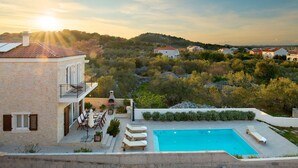 A villa with a swimming pool, outdoor seating, and a view of the surrounding landscape. - Villa Galleon with Pool (Murter)