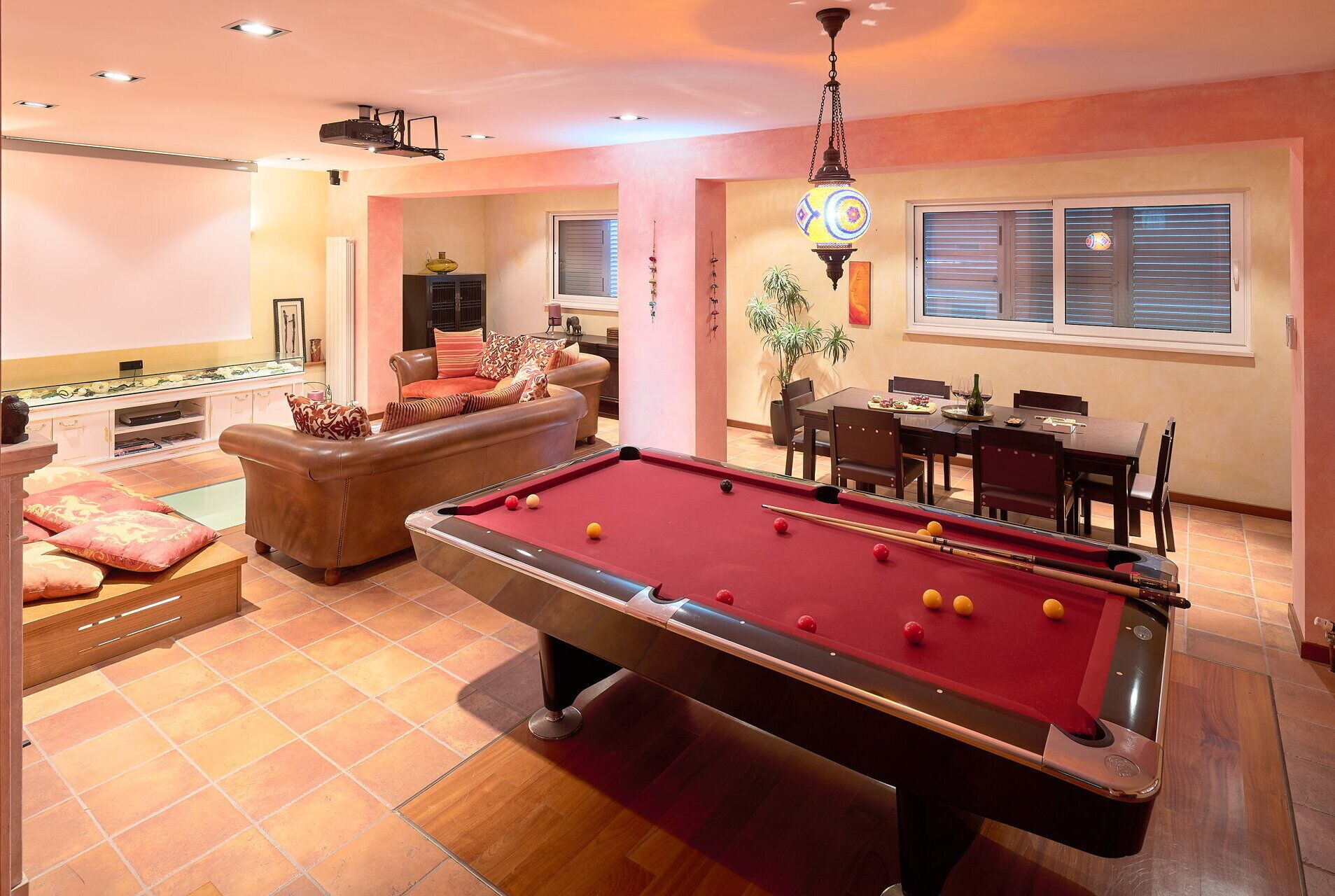 Une table de billard dans une pièce bien éclairée, avec un canapé et un coin repas en arrière-plan.